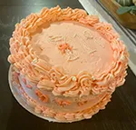 vintage vanilla 19th birthday cake with pink buttercream frosting, piped details around the sides and pearl sprinkles forming a martini glass on the cake center